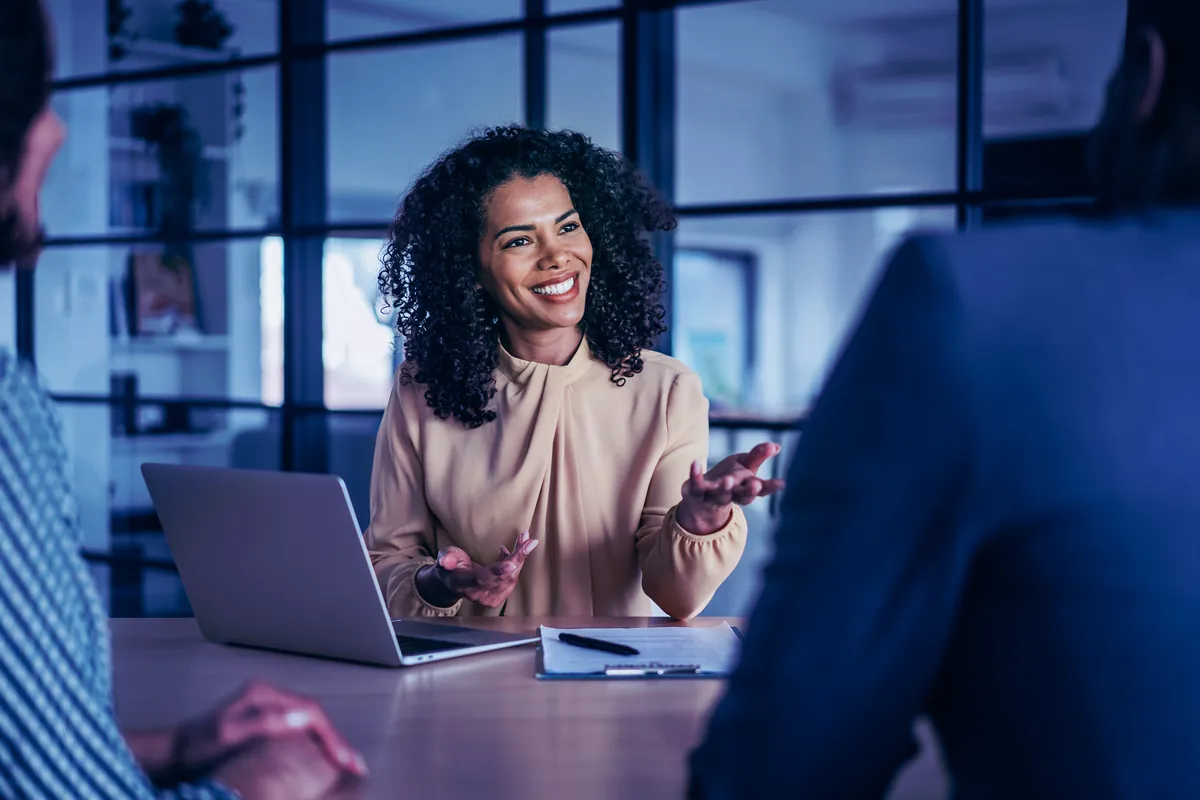 Une responsable CRM échange en réunion, le sourire aux lèvres